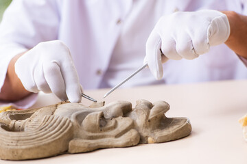 Young male archaeologist studying ancient african stonemask