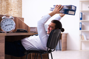 Young male employee unhappy with excessive work in the office