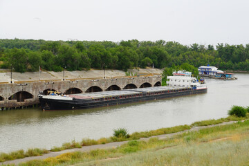 Fototapeta na wymiar Cargo transportation by water transport. The dry cargo ship is standing at the quay of the canal lock wall and is waiting for its turn to lock. Volga-Don Shipping Canal. Volgograd. Russia.