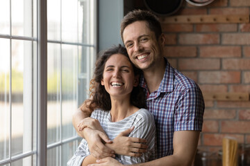 Close up portrait of smiling young Caucasian family man and woman hug in own house. Happy...