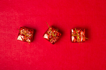 Fototapeta na wymiar Christmas decorations on a red background. Holiday decorations. Three red gifts on a red background. Christmas concept