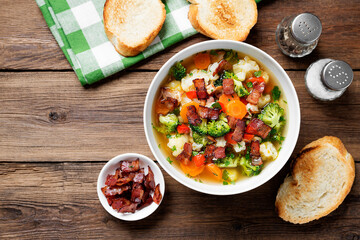 Soup with broccoli and cauliflower served with smoked bacon and toasted bread.