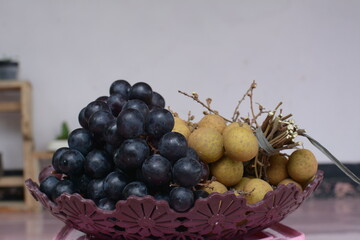 grapes and longans on a plate on a white background