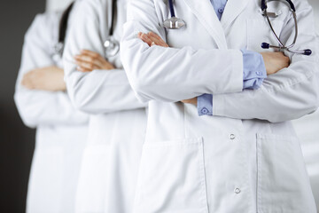 Group of modern doctors standing as a team with arms crossed in hospital office and ready to help patients. Medical help, insurance in health care, best disease treatment and medicine concept