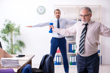 Two employees doing physical exercises at workplace