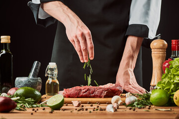 Man adds rosemary onto a piece of meat