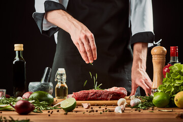Chef throws rosemary onto raw meat. Uncooked beef steak