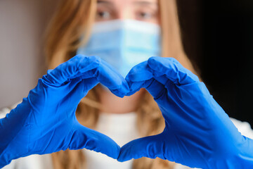 Horizontal shot of a heart symbol formed by hand of the doctor in protection blue gloves. 