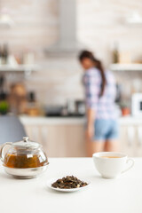 Woman preparing tasty food for breakfast in kitchen and using aromatic herbs for green tea. Shot with background blur of lady having great morning with tasty natural healthy herbal tea sitting in the