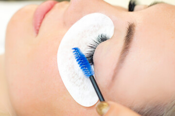 Eyelash extension procedure. Beautiful woman with long eyelashes in a beauty salon. Eyelashes close up. brush in the hands