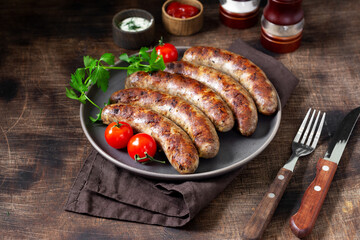 Fried sausages. Grilled sausages with spices, sauce, tomatoes and parsley. Delicious meat sausages in a ceramic plate	