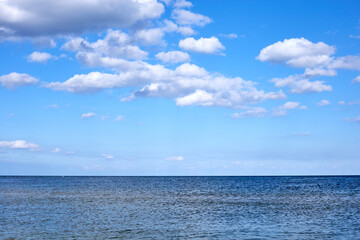 Naklejka na ściany i meble calm sea waters against a blue sky with clouds