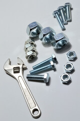 screw-nut of different sizes, bolts and adjustable spanner. White background.