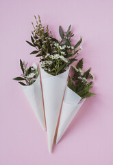 white flowers in paus tracing paper cone on pink background