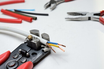 wire stripper, shielded three-core wire and wire cutters on a white background. close-up