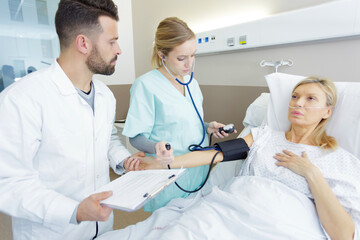 Obraz premium caring medical doctor taking mid age womans blood pressure