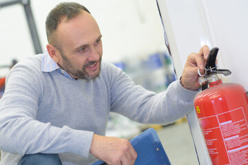 male hands pulling safety pin of fire extinguisher