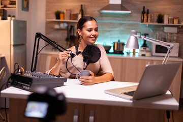 Social media analyst speaking on microphone during podcast with neon light in the background, recording. Online show On-air production internet broadcast host streaming live content.