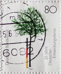 GERMANY - CIRCA 1988: a postage stamp from Germany, showing a planted tree with a support in black-red-gold the colors of the German flag. 25 years of the German Development Service (DED)