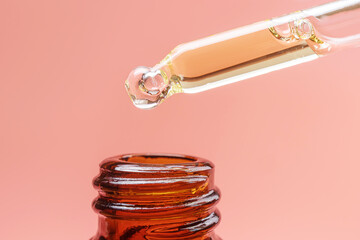 Pipette with essential oil on a pastel pink background. The concept of beauty, skin care,...
