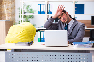 Young male employee looking after newborn at workplace