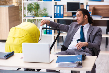Young male employee looking after newborn at workplace