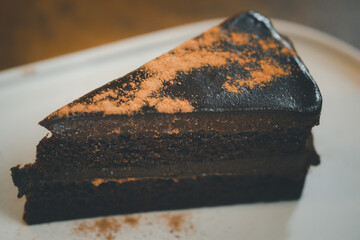 Close up triangle slice piece of delicious dark chocolate fudge cake