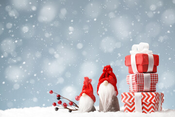 Christmas gnomes with gift boxes on the snow background