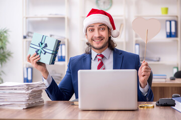 Young male employee working in the office at Christmas Eve