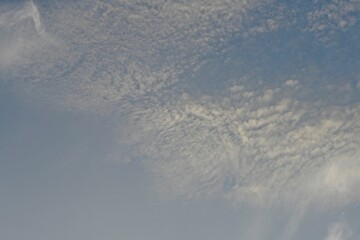 Light blue sky with light gray and white clouds in diffused light