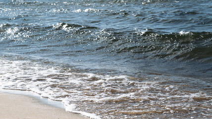 beautiful sandy beach of the lake and blue waves in the storm of the sea
