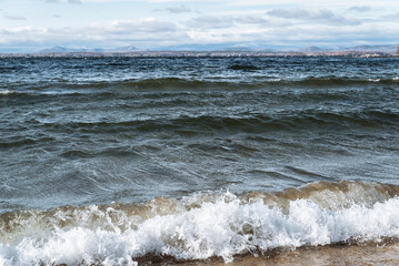 Fototapeta premium beautiful sandy beach of the lake and blue waves in the storm of the sea