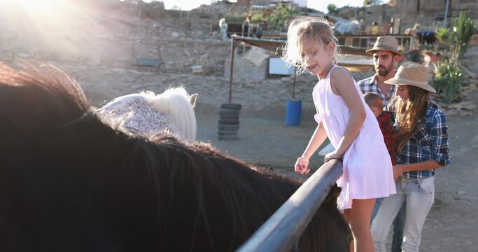 Happy family having fun cuddling horses at farm ranch - Slow Motion