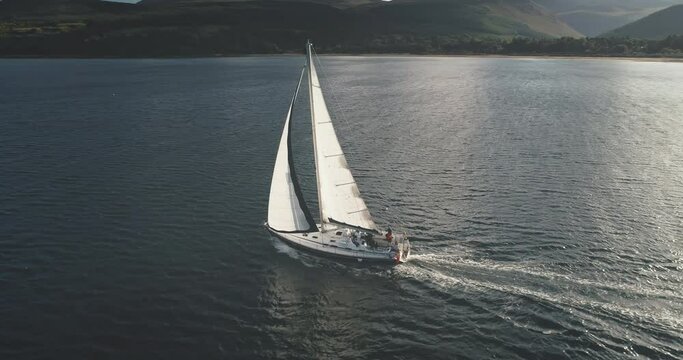 Sun light at sea bay with luxury yacht reflection aerial. Epic passenger sailboat cruise at open ocean. Tourism and travel lifestyle. Summer vacation scenery at sunshine. Cinematic seascape
