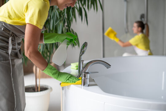 Professional Cleaning Of The Bathroom And Toilet. Cleanliness And Hygiene At Home. Cleaning Service And Housekeeping. Hand In Green And Yellow Latex Gloves. Rubbing The Bathroom And Taps