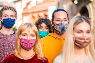 Group of multirracial friends walking atwalking at city streets - New normal travel concept with young people covered by protective mask - Focus on asian man