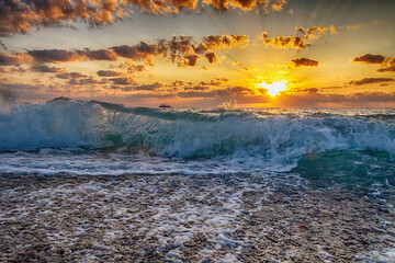 Beautiful clouds over the sea, sunrise and splashing waves.