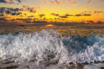 Beautiful clouds over the sea, sunrise and splashing waves.