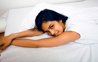 pretty indian brunette real woman in bed smiling, white sheets, tann skin close up  cant sleep