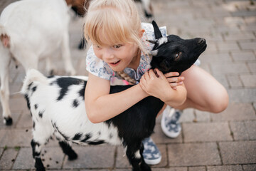 Mädchen umarmt eine kleine Ziege