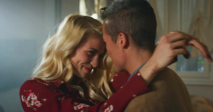 Cinematic shot of young carefree happy smiling homosexual female gay and transgender man couple in love is enjoying time together and having fun to dance together while listening to the music at home