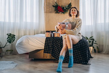 Happy and pretty brunette on the bed with gift boxes around her.