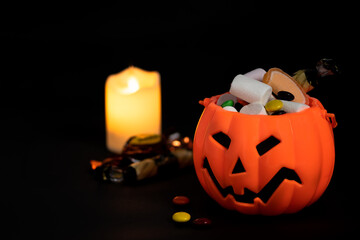 candies and sweet things in jack o lantern with some  snacks in front of a candle