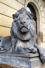decorative bronze statue of a male lion in front of a building. 