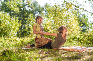 Woman masseuse demonstrates refreshing massaging methods in the forest.