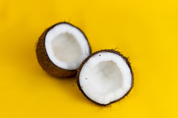 Halves of coconut on yellow background