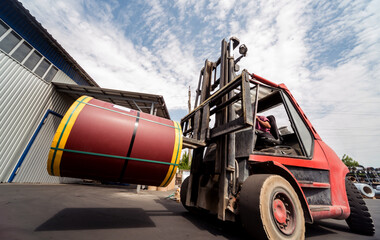 The forklift is handling big metal coil to warehouse.