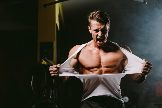 powerful man tearing shirt. Bodybuilder man pumping muscles and ripping shirt in gym. Hot and handsome man tearing shirt with anger and furious. Fitness motivation background