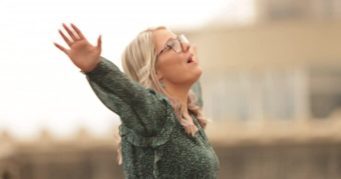 Closeup, Slow motion, Young,  Beautiful Girl with Blonde Hair, in Glasses Singing on the Roof Top  of the Empty Parking lot, Downtown Portland, Oregon, September 2020, Smoking Air background,4K 