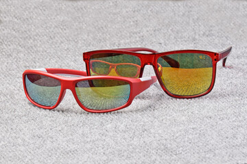 Men's and children's sunglasses lie on a fleecy fabric surface